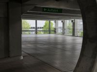 an underground parking lot with a green arrow sign in the middle of the road on a flat surface