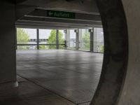 an underground parking lot with a green arrow sign in the middle of the road on a flat surface