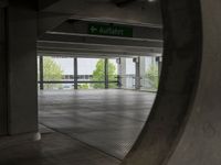 an underground parking lot with a green arrow sign in the middle of the road on a flat surface