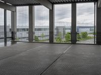 an indoor room with floor to ceiling glass and grey tile floors with large windows on the left