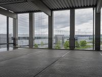 an indoor room with floor to ceiling glass and grey tile floors with large windows on the left