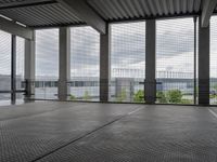 an indoor room with floor to ceiling glass and grey tile floors with large windows on the left