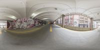 a fish eye view of a parking garage with a ramp and graffiti on the walls