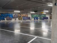 an empty parking garage with colorful graffiti on it's walls and floor, as well as the words