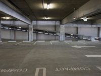 a parking garage with parking spaces marked in white on the floor area where the cars are parked