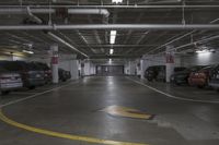 a parking garage with multiple cars parked under ceiling lights and overhead lighting above a circular, yellow striped parking spot