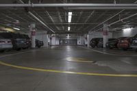 a parking garage with multiple cars parked under ceiling lights and overhead lighting above a circular, yellow striped parking spot