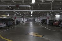 a parking garage with multiple cars parked under ceiling lights and overhead lighting above a circular, yellow striped parking spot