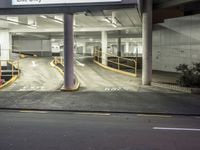 empty parking garage area and road at night time with lights on it's posts