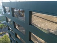 a green building and stairs from below view through two bars of glass that run down the center of the walkway