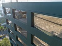 a green building and stairs from below view through two bars of glass that run down the center of the walkway