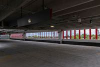 an empty parking garage in an unfinished building with lots of windows and some red and white poles