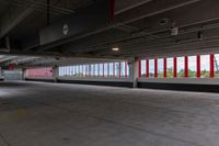 an empty parking garage in an unfinished building with lots of windows and some red and white poles