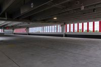 an empty parking garage in an unfinished building with lots of windows and some red and white poles