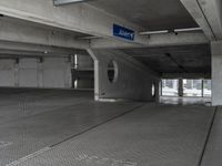 a parking garage with cement flooring and large metal poles, near some windows and light