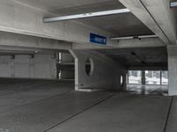 a parking garage with cement flooring and large metal poles, near some windows and light