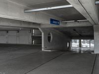 a parking garage with cement flooring and large metal poles, near some windows and light