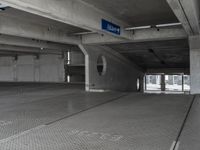 a parking garage with cement flooring and large metal poles, near some windows and light