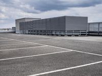 there is a long storage unit with boxes in the parking lot attached to the side of the building