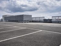 there is a long storage unit with boxes in the parking lot attached to the side of the building