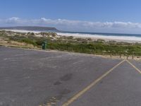 a parking lot with a beach in the background and an ocean on the left side