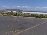 a parking lot with a beach in the background and an ocean on the left side