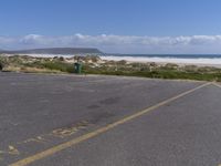 a parking lot with a beach in the background and an ocean on the left side