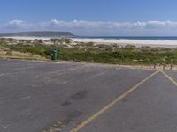 a parking lot with a beach in the background and an ocean on the left side