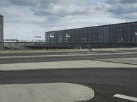 a parking lot near a building under a blue cloudy sky with white clouds above it