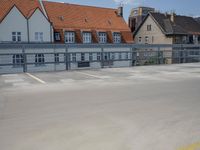 a parking lot with yellow and red cars parked on the road, a blue fence, and other houses