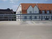 a parking lot with yellow and red cars parked on the road, a blue fence, and other houses