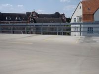 a parking lot with yellow and red cars parked on the road, a blue fence, and other houses