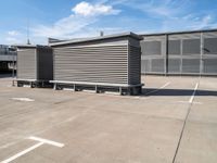 a parking lot in front of a large industrial building with striped steel fenced doors