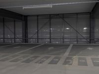 a parking garage is empty and has lights on the ceiling and inside of it are black walls and grey concrete