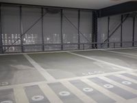 a parking garage is empty and has lights on the ceiling and inside of it are black walls and grey concrete