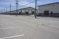 an empty parking lot with two buildings in the background and telephone poles and lights on the sides