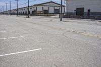 an empty parking lot with two buildings in the background and telephone poles and lights on the sides