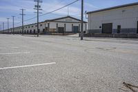 an empty parking lot with two buildings in the background and telephone poles and lights on the sides