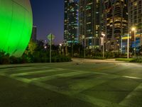 empty parking lot with buildings in the background and green lighting from street lamps at dusk