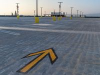 a sign pointing left at the parking lot of an airport runway with lots of parking spaces