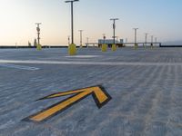 a sign pointing left at the parking lot of an airport runway with lots of parking spaces