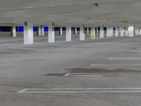 a parking lot with many parked cars and white columns with colorful signs hanging off the ceiling