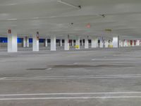 a parking lot with many parked cars and white columns with colorful signs hanging off the ceiling