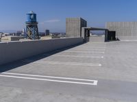 an empty parking lot with no grass or building to the side and blue water tower in the distance