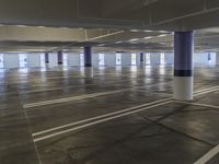 there is no parking space in this large garage building on the floor with only white lines, and there is no floor