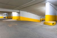 an empty parking garage with concrete floors and yellow painted accents painted in white and yellow