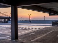 a parking lot near the ocean at dusk with a building in the back ground at the center