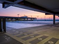 a parking lot near the ocean at dusk with a building in the back ground at the center