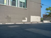 a paved street has been painted light gray, with gray brick walls and concrete edges