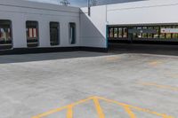 an empty parking lot is shown with several windows and a yellow line across the sidewalk